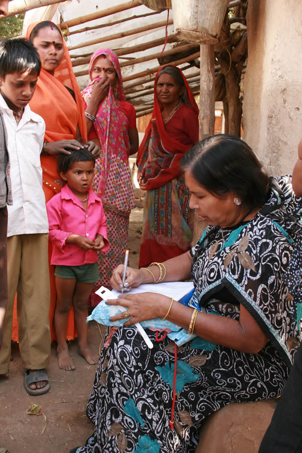 A woman writes on a medical form while a family watches