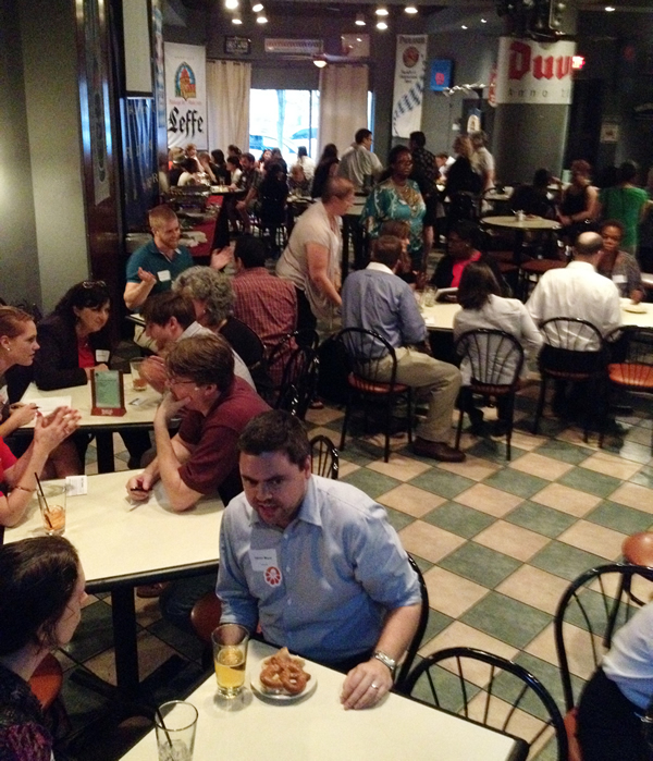 Photo of a room full of people networking at small tables.