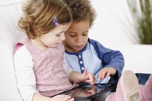 Two young children using a tablet.