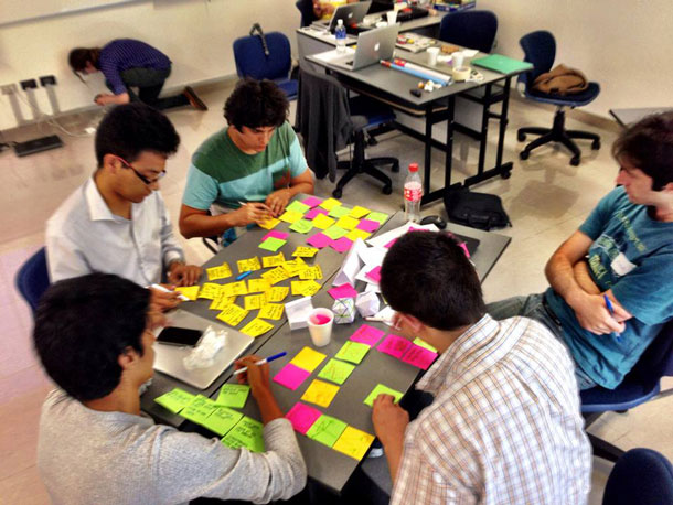 A small group works around a table, with colored Post-it notes.