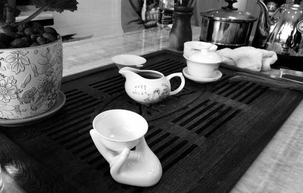 A tea set arranged on a tray. one cup is held in a porcelain hand