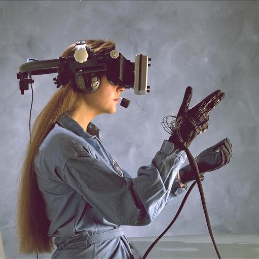 A woman wearing a helmet with a screen in front of her eyes, and gloves with sensor cables.