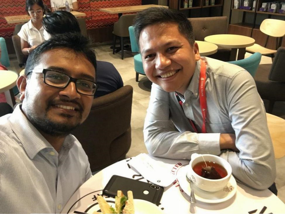 Photo of two people smiling for the camera while sharing a meal.