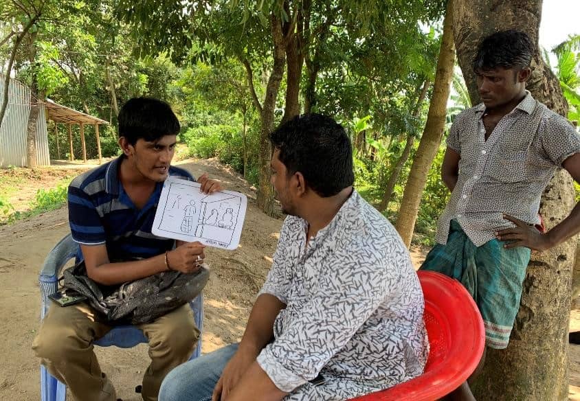 Photo of a person showing and discussing a picture with two other people.